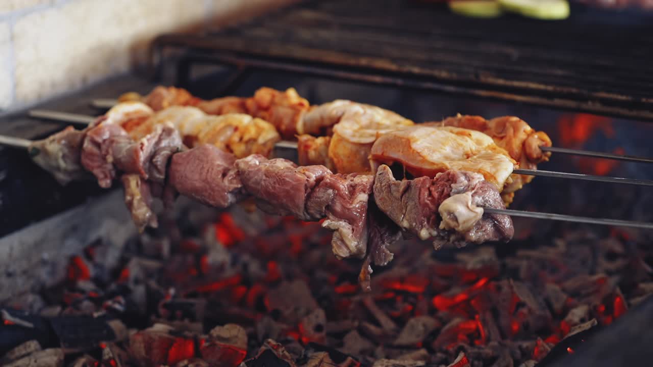 Meat cooking on charcoal. Delicious barbeque on metal skewers. Process of frying juicy meat. Close-up.