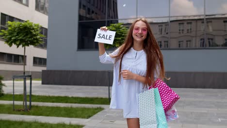 beautiful young girl showing black friday inscription, smiling, looking satisfied with low prices