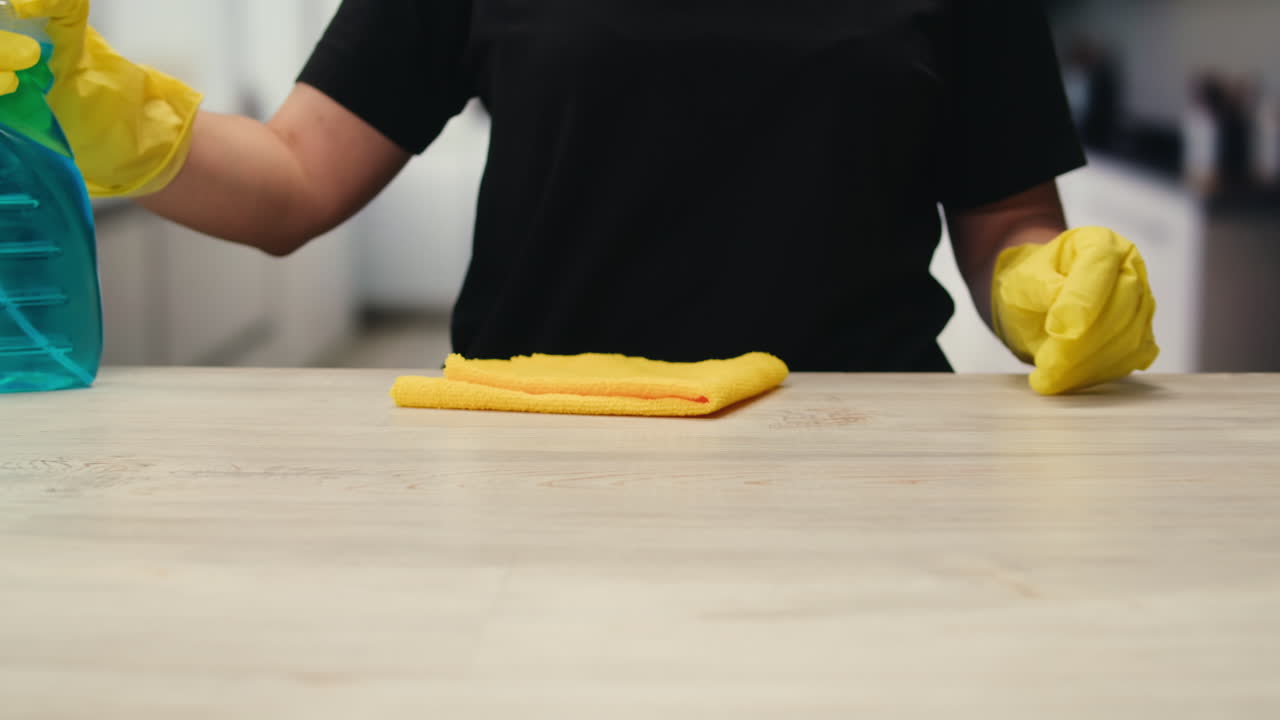 Person in Yellow Gloves Spraying and Wiping Kitchen Counter