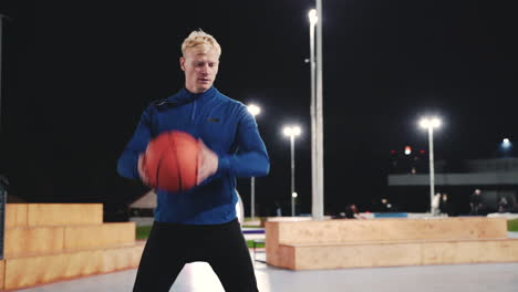 Sportlicher-Blonder-Mann,-Der-Nachts-Im-Park-Mit-Basketball-Trainiert