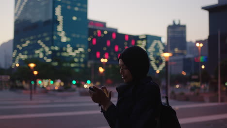 portrait of young mixed race woman taking photo of city office building sightseeing using smartphone mobile technology enjoying evening urban travel