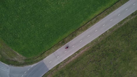 aerial drone shot of motorcyclist driving down a bend road