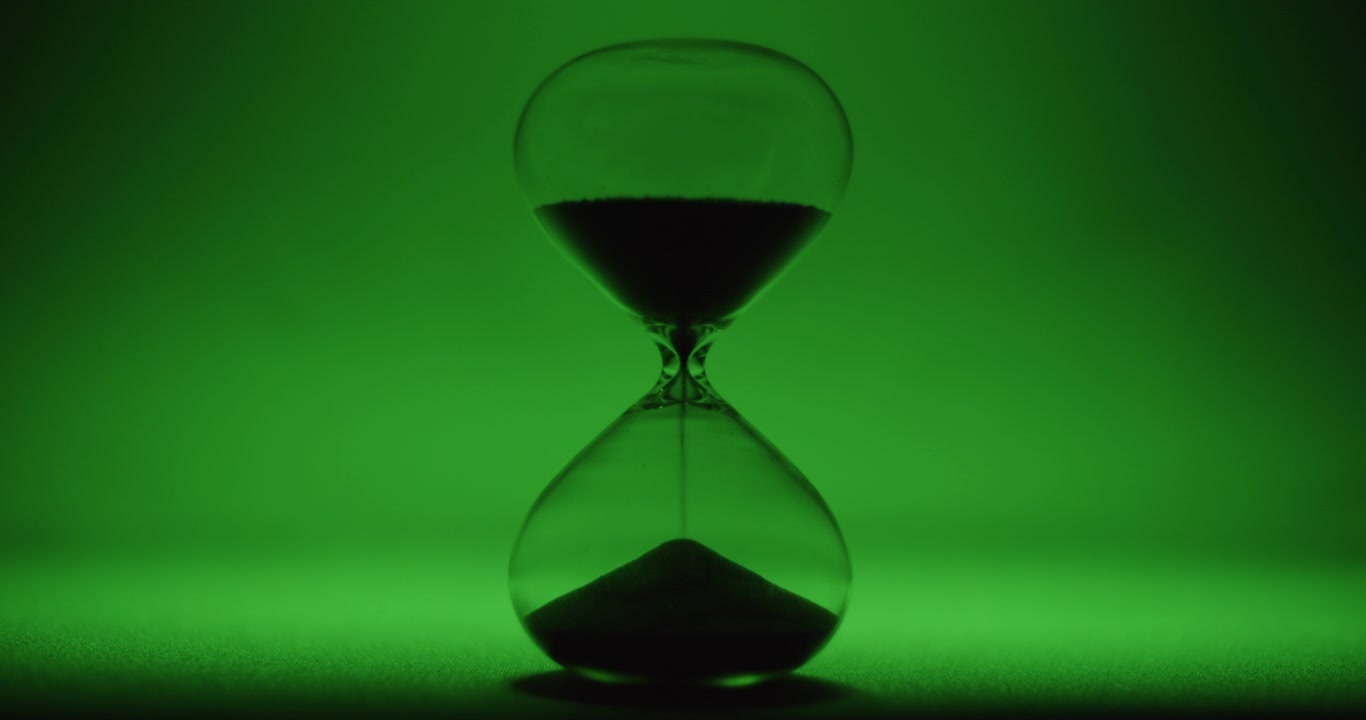 Hour glass on emerald colored background