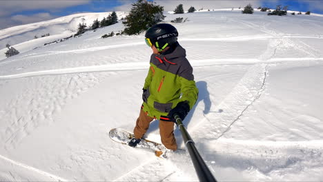 male snowboarder goes down the snowy slope quickly. sportsman takes selfie of his ride and beautiful landscape around.