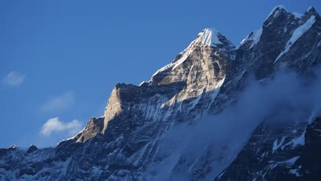 close up of the icy rocky summit of langtang lirung against a blue sky