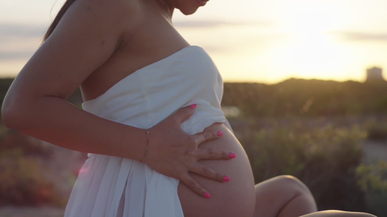 Peaceful close-up of a pregnant woman in white, surrounded by soft golden hour light near Albufera Lake, Spain.