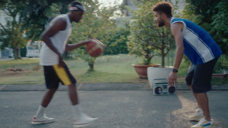 two friends playing basketball outdoors, black man scoring