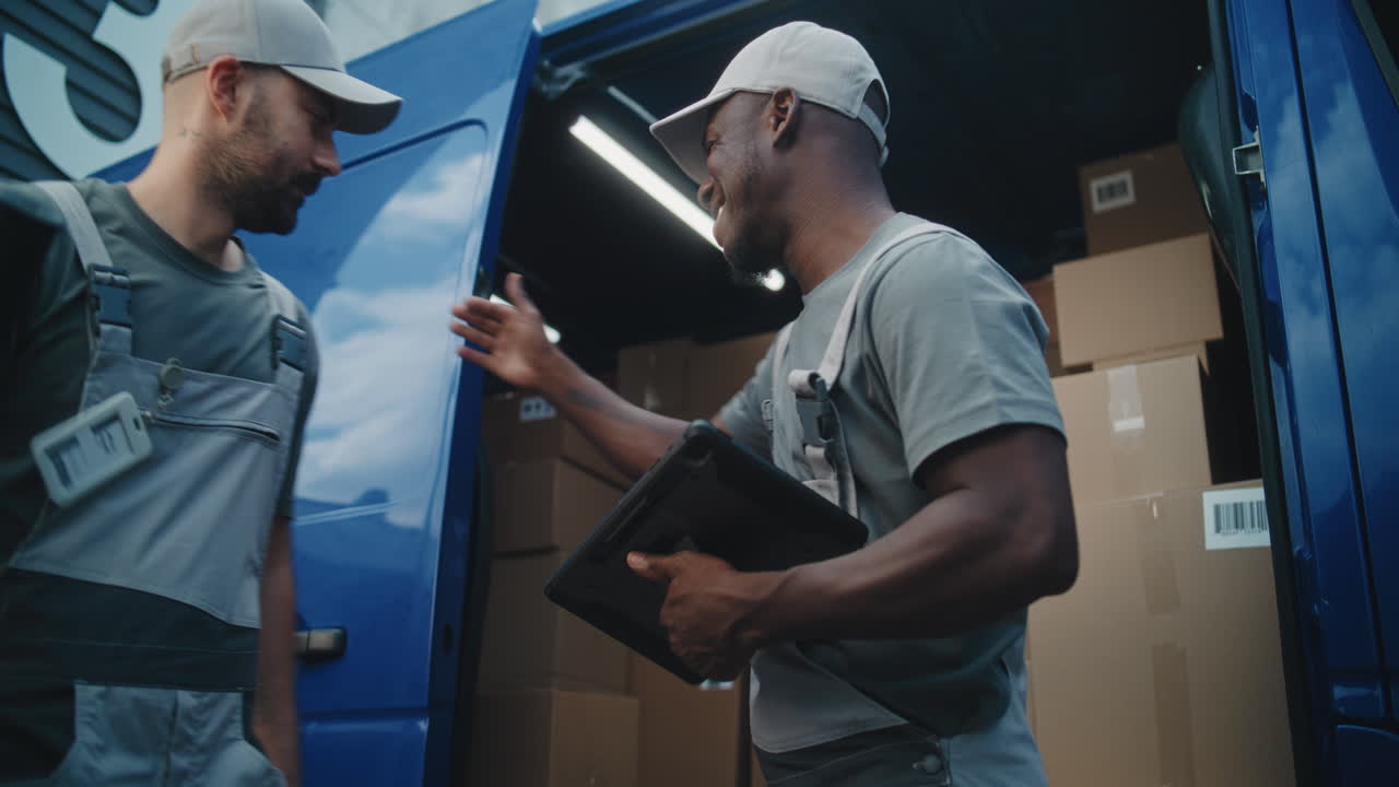 Delivery Workers Using Tablet Next to Van