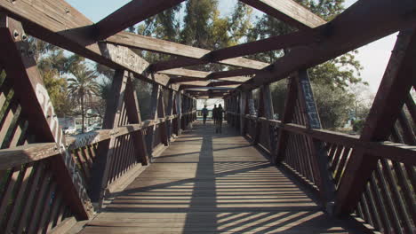 Puente-De-Madera-Moderno-Sobre-Una-Carretera-Con-Gente-Pasando