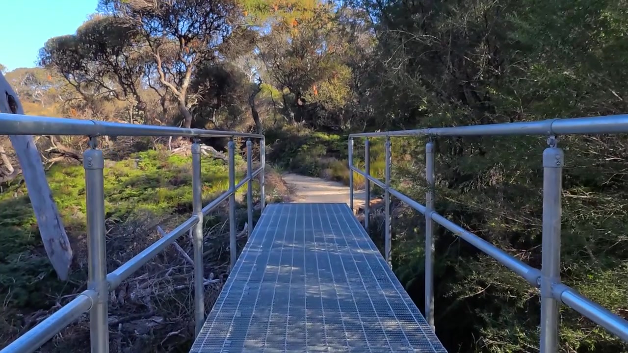 Attraversare una passerella metallica su un sentiero nel bosco.