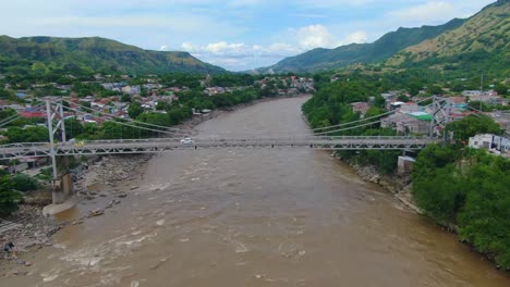 large suspension bridge in central america over rough river as birds soar in sky