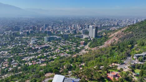 aerial view from hillside overlooking residential and commercial areas of santiago with lush greenery and city skyline in the distance