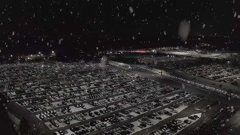 snow falls on huge parking lot full of cars in winter