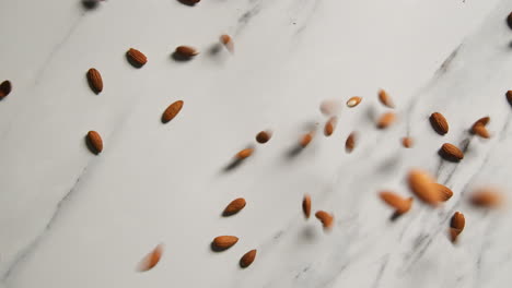 fotografía aérea de nueces de almendra cayendo sobre una superficie de mármol tomada en cámara lenta