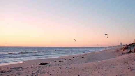 los surfistas de kitesurf navegan en la ola del océano al atardecer, bloubergstrand, ciudad del cabo, sudáfrica