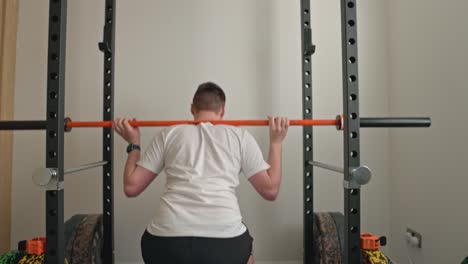 static shot of a man doing a warmup set of barbell squats with no weight