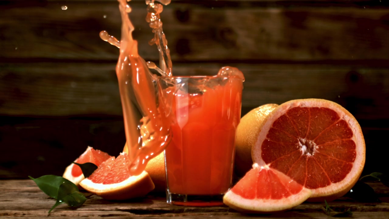 Succo di pompelmo fresco che schizza e si versa su un tavolo di legno.