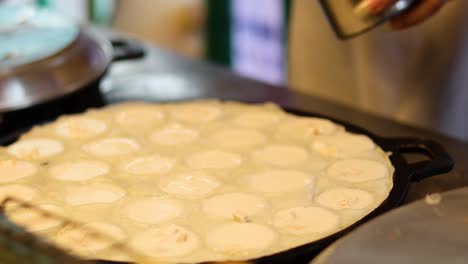 preparing traditional thai coconut pudding on hot griddle