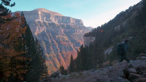 Hiker-man-with-trekking-backpack-walking-on-trail-in-autumn-woods-and-mountains-in-Ordesa-National-Park,-Spain