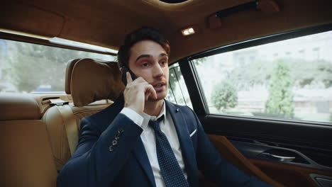 portrait of smiling businessman calling on phone inside modern car