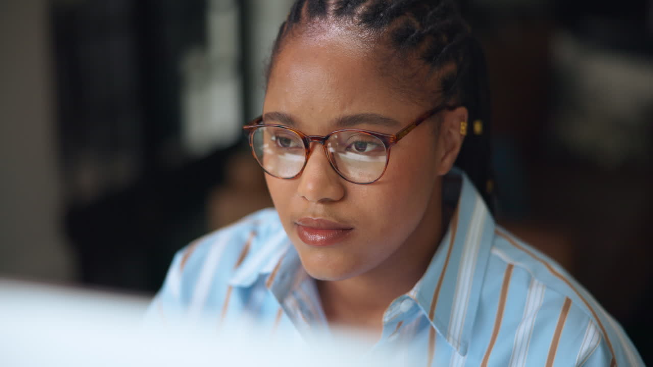 Young Black Woman Puts on Glasses and Focuses