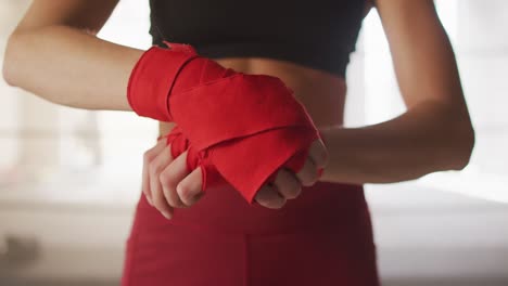 Video-De-Manos-De-Una-Mujer-Caucásica-Atando-Cintas,-Preparándose-Para-El-Entrenamiento-De-Caja-En-El-Gimnasio