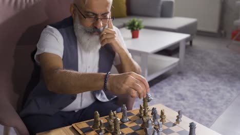 mature man playing chess alone at a table at home.