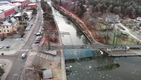 aerial drone shot of vehicles driving on road beside trollhätte canal connecting göta river with the lake vänern during cold winter day in sweden