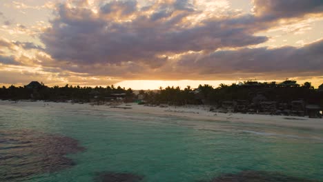 aerial view over akiin beach in tulum, mexico while people enjoy the sunset on the beach