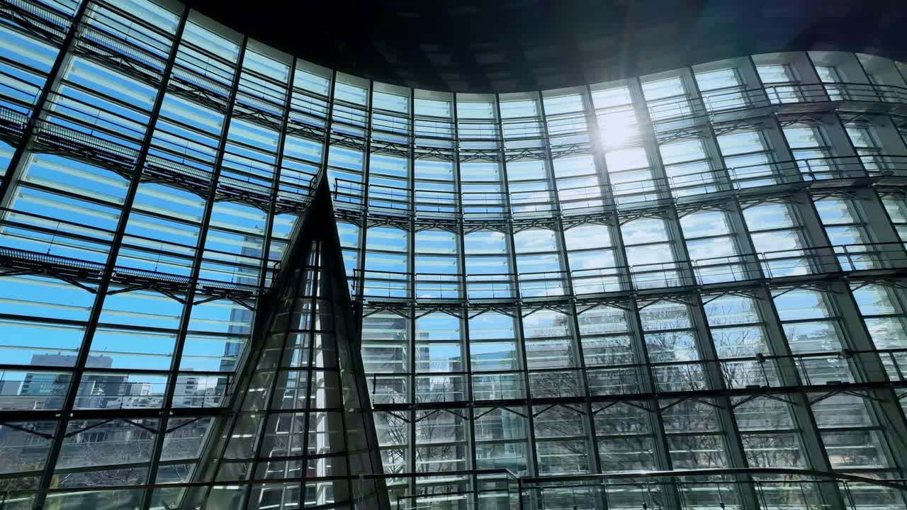Glass atrium of The National Art Center, Tokyo, with curved architecture and sunlight