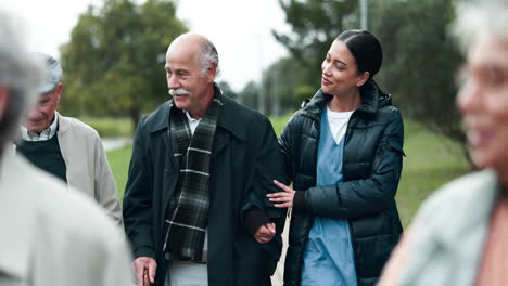 nurse assisting elderly people walking in park