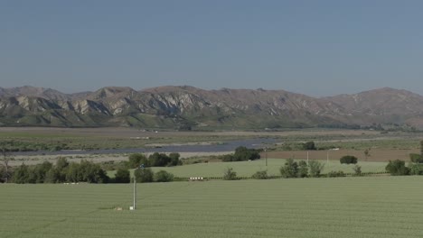 aerial drone footage of vast green onion farm, scenic hills, blue sky