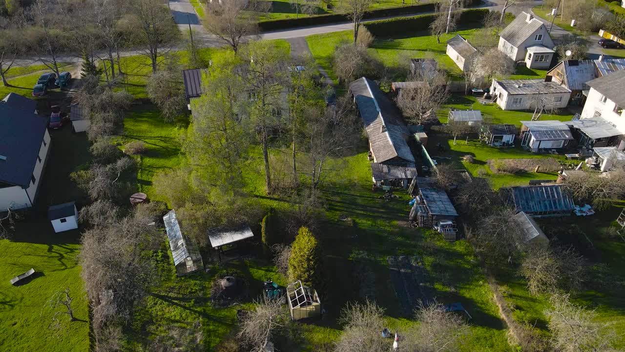 Aerial footage of the borough of Saku, residential house exteriors and yards. View from above private house areas with green lawn backyards and greenhouses. Spring outside scenery around neighborhood