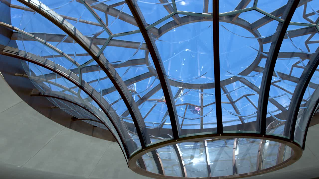 Low angle shot of a geometric glass skylight dome against a clear blue sky