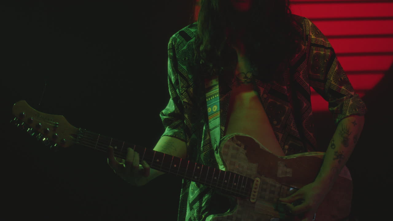 Rock Musician Playing the Guitar in Dark Studio with Neon Illumination