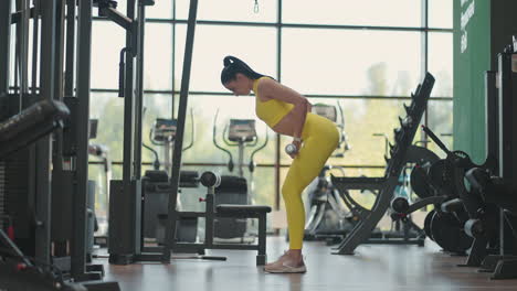 mujer hispana realizando barra doblada sobre fila. mujer de fitness entrenando fila doblada sobre fila aka doblada sobre fila aka fila de barra. entrenar los músculos de la espalda con una barra mientras está de pie en una inclinación