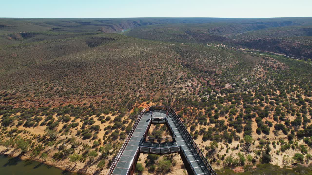 4K drone view flying over the skywalk in Kalbarri National Park, Western Australia, as a couple walk down the popular tourist destination. There are stunning natural views all around the skywalk.