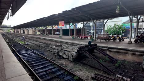 view of the kandy railway station platform in sri lanka, featuring railway tracks, concrete sleepers, and an empty platform. a peaceful, serene atmosphere in a typical sri lankan train station.