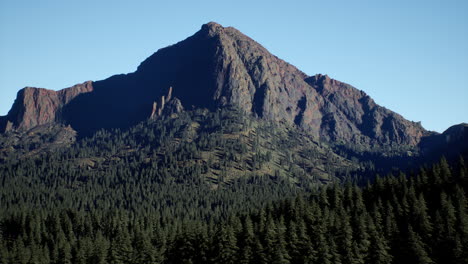 panoramic aerial view of rocky ridge among green forest at sunset