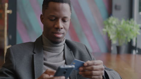 man making a mobile payment in a cafe