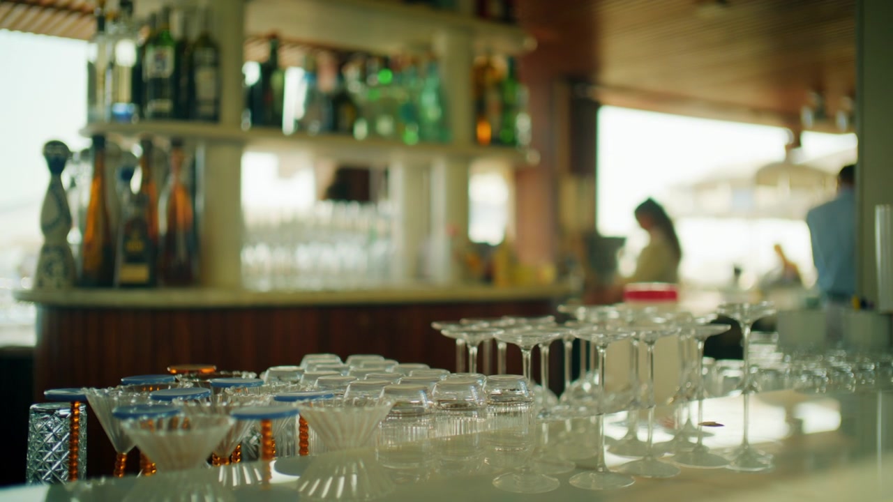 Close-up of empty wine and cocktail glasses on a bar counter with bottles behind, Cannes, France
