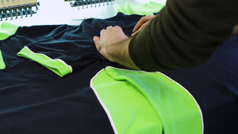 male worker checking the sewing on cotton t-shirts