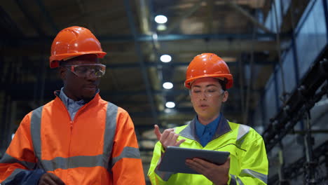 partners holding tablet computer walking at huge modern manufacturing storage.