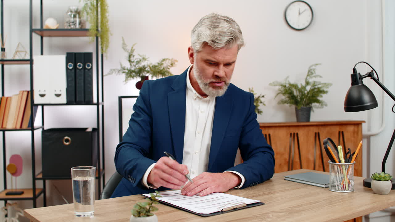 Middleaged businessman spots invoice error fixes figures with pen then signs key papers confidently