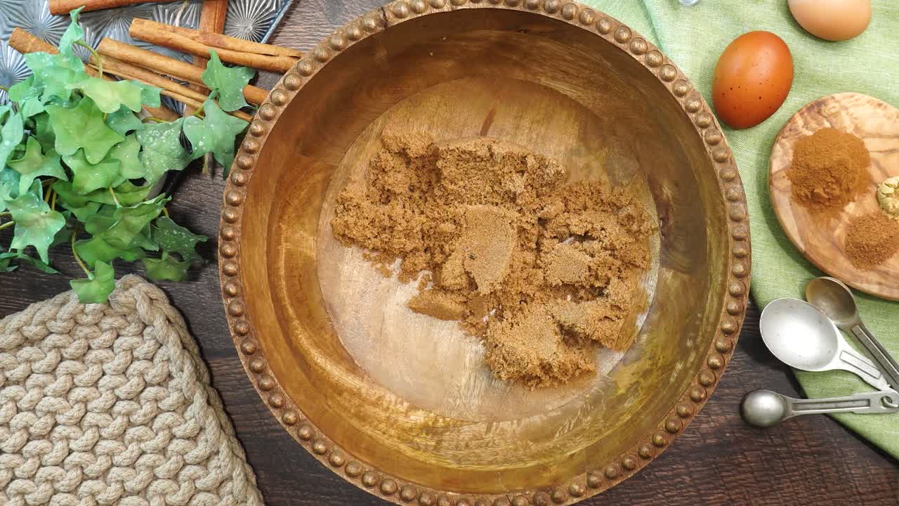 Baking a carrot cake loaf with cream cheese icing and topped with roasted salted pecans. Making a Autumn dessert with carrots, flour, sugar, nuts and frosting. Adding vegetable oil to the batter.