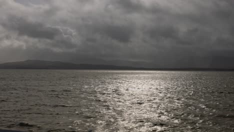 hand-held shot of moody clouds with sun shining through at the scottish coast