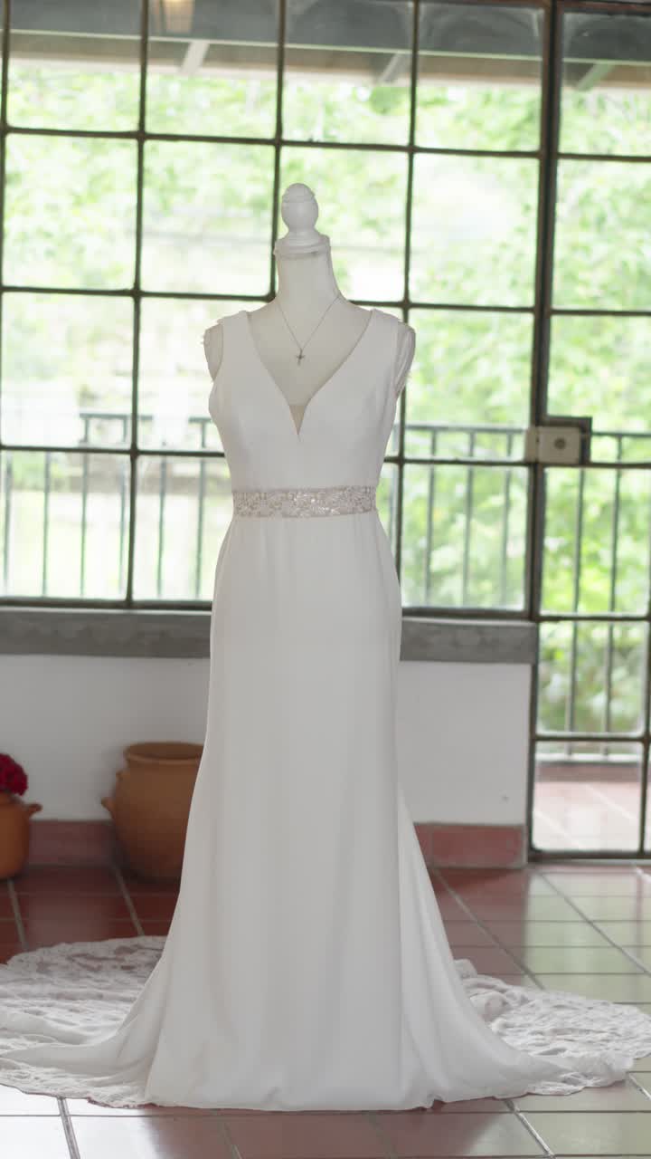 Long white wedding dress displayed on mannequin in country house room. Elegant wedding fashion.