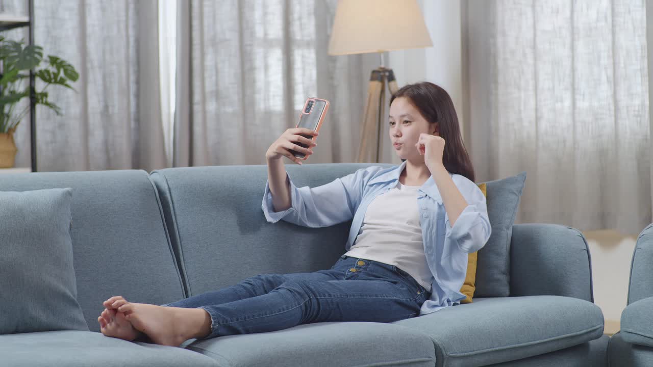 소파에서 셀피를 찍는 젊은 여성