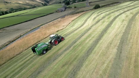 hermoso punto de vista aérea de un tractor de cosecha con rollo negro que funciona en un amplio campo de hierba en verano