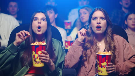 chicas conmocionadas mirando thriller en el interior